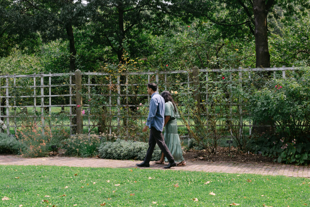 Couple walking together at the Brooklyn Botanic Garden during their surprise proposal and engagement session in New York City.
