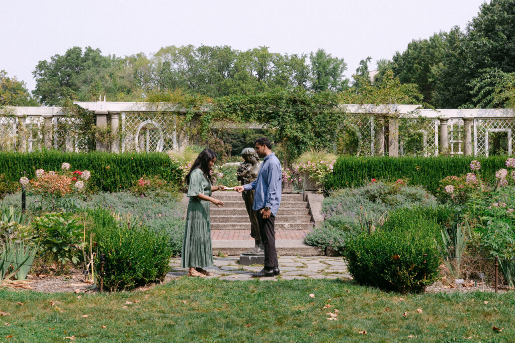 Wide shot of a surprise proposal in the Rose Garden at Brooklyn Botanic Garden, captured by NYC proposal and engagement photographer.
