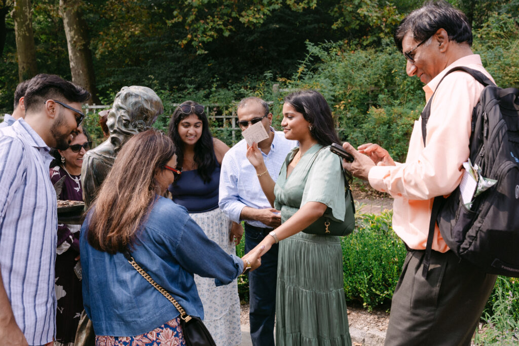 Family congratulating the bride-to-be after a surprise proposal at Brooklyn Botanic Garden Rose Garden, captured by NYC engagement photographer.
