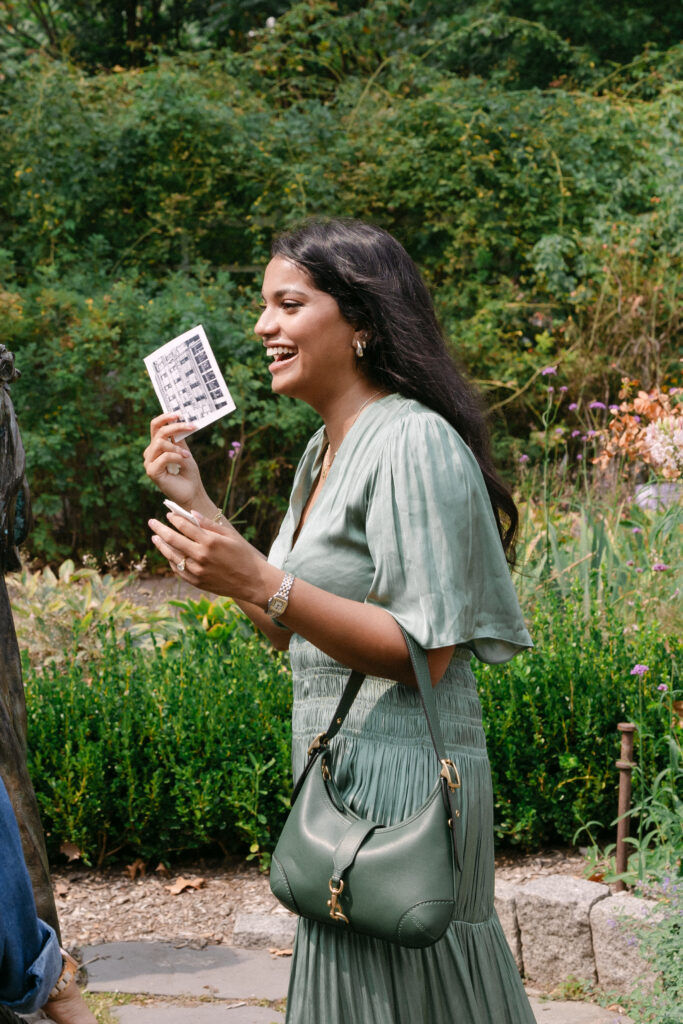Bride-to-be smiling and holding her engagement ring box after a surprise proposal at Brooklyn Botanic Garden, captured by NYC engagement photographer.
