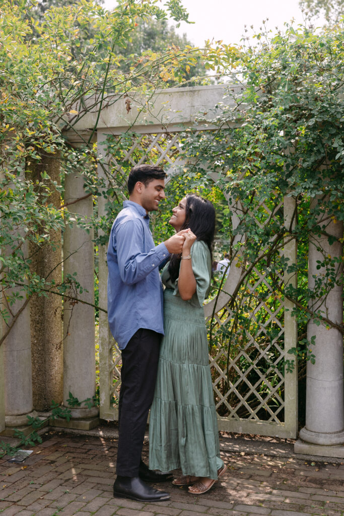 Engaged couple sharing a candid moment at the Rose Garden in Brooklyn Botanic Garden, photographed by NYC proposal and engagement photographer.
