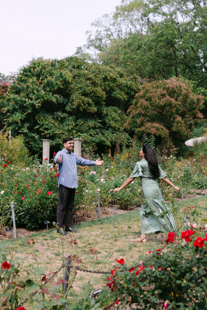 Engaged couple walking hand in hand through the Rose Garden at Brooklyn Botanic Garden, captured by NYC engagement and proposal photographer.
