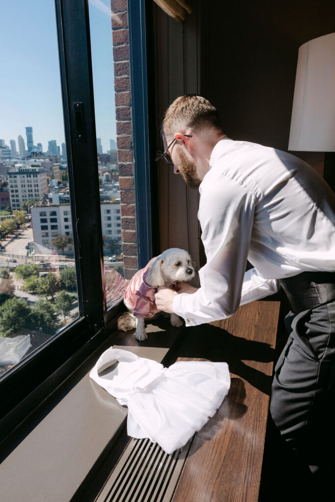 Groom getting ready by a window with city views during a SoHo wedding in New York City