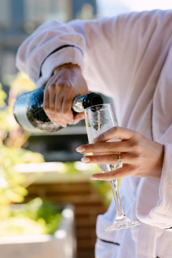 Bride pouring champagne while getting ready at the SoHo Grand Hotel
