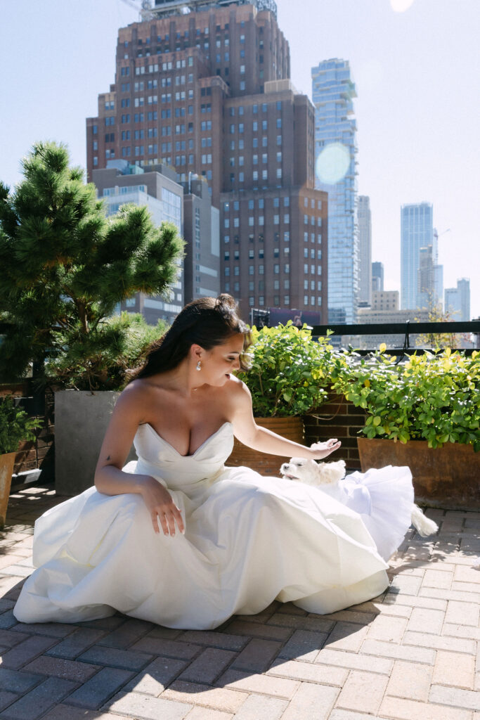 Bride sitting on a SoHo rooftop terrace with New York City skyline during wedding day portraits