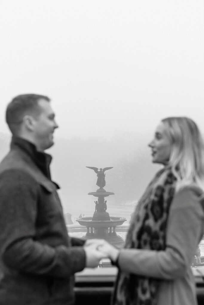 black and white portrait of an engaged couple holding hands in central park after a surprise proposal