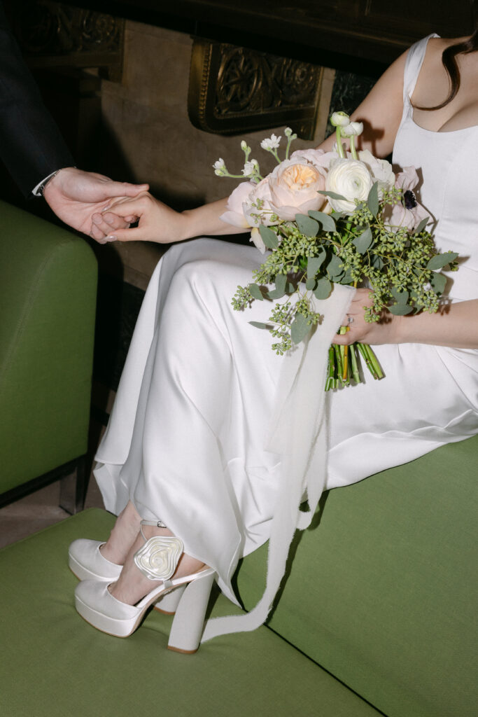 Wedding bouquet and shoes resting on a green bench after city hall ceremony