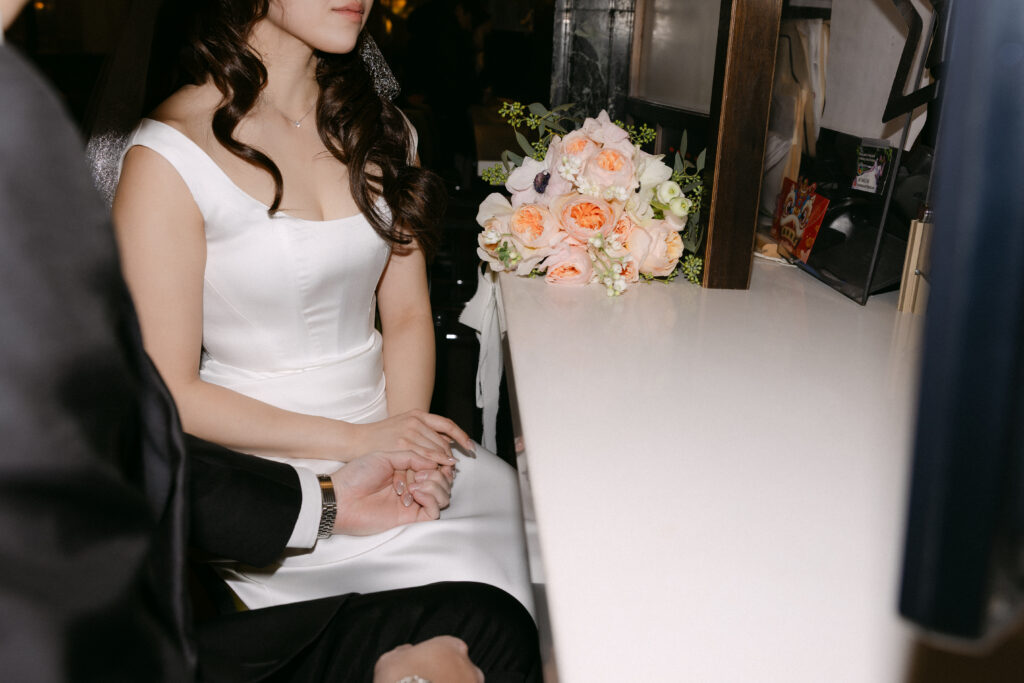 Bride sitting on the NYC subway holding her bouquet after city hall wedding