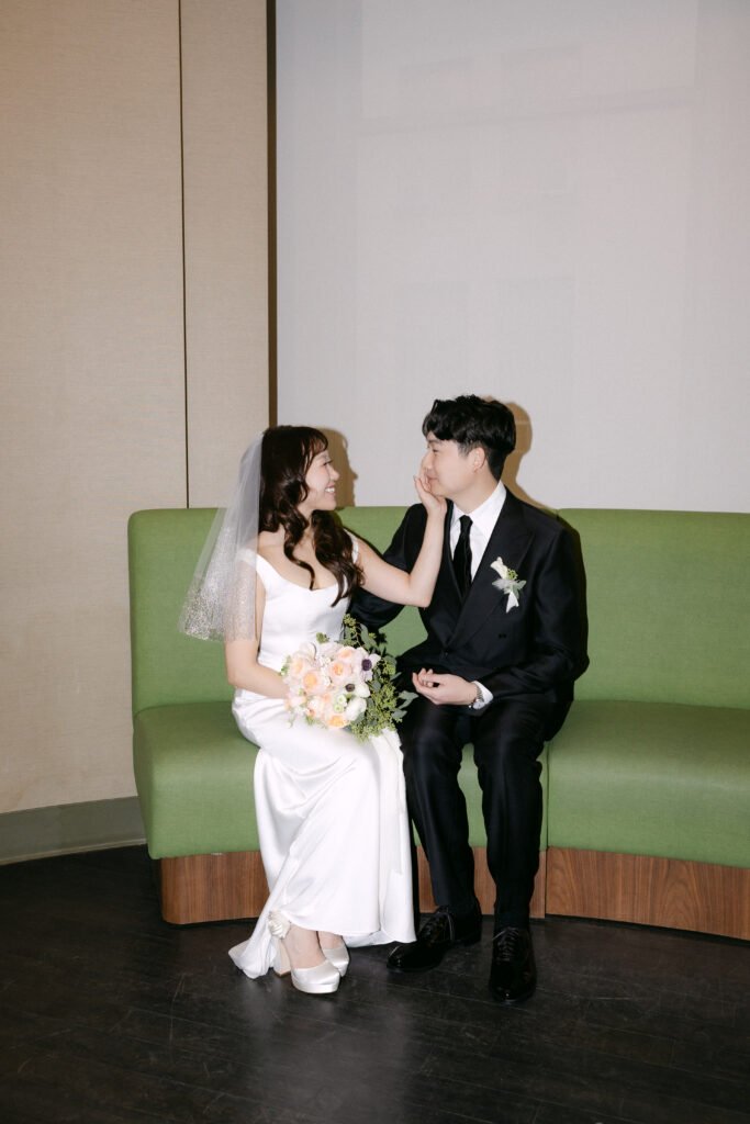 Couple sitting together inside NYC City Hall on a green bench