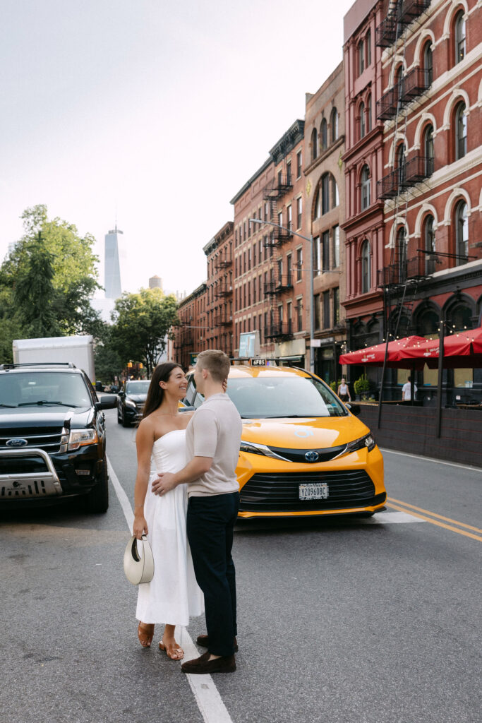 west village engagement photos with a couple standing in the street and a yellow taxi in new york city
