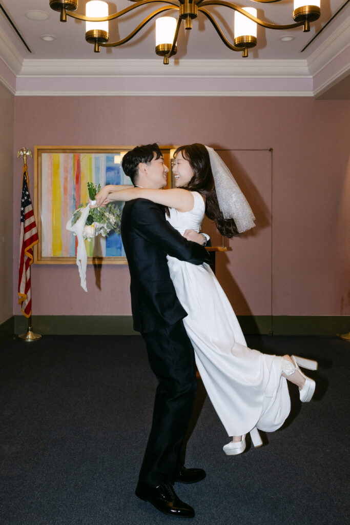 Groom lifting the bride inside NYC City Hall
