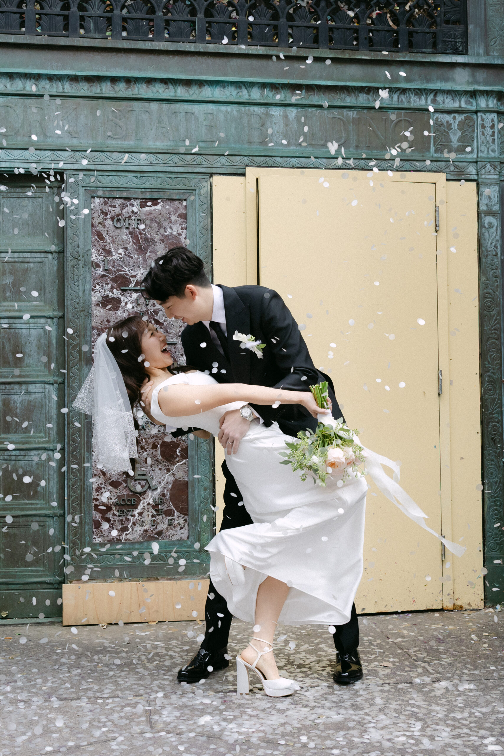 Just married couple exiting NYC City Hall with confetti and family cheering