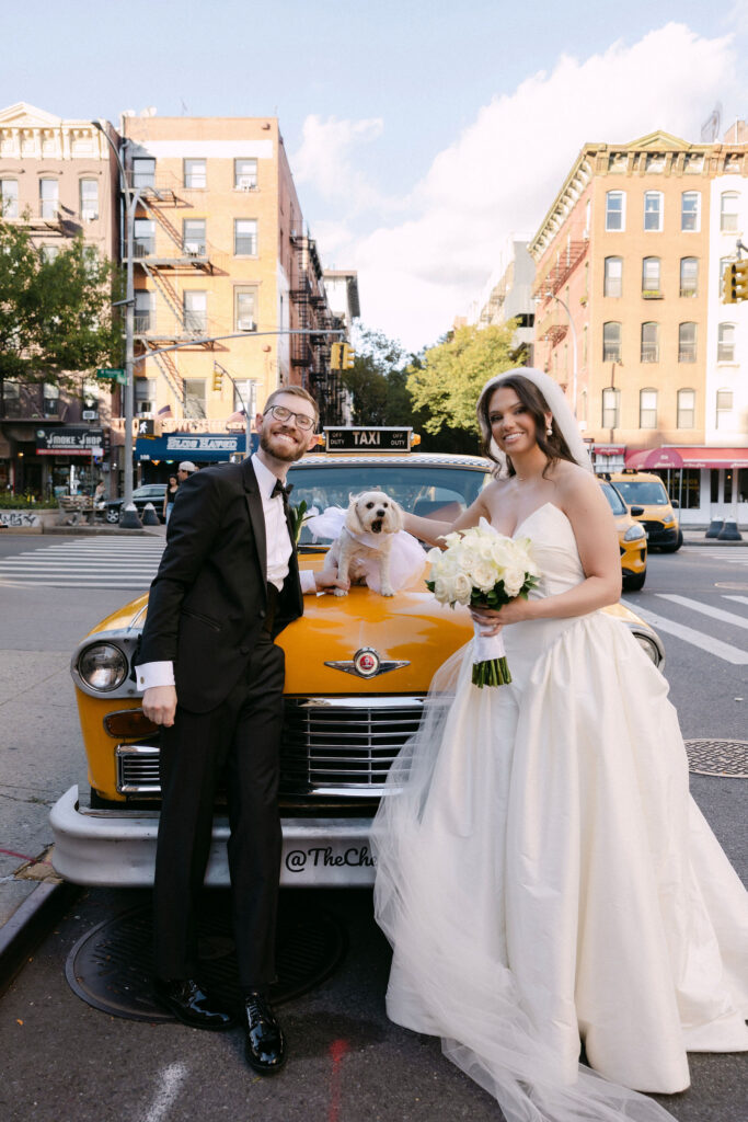 Bride and groom posing with a yellow vintage taxi during SoHo wedding portraits in New York City
