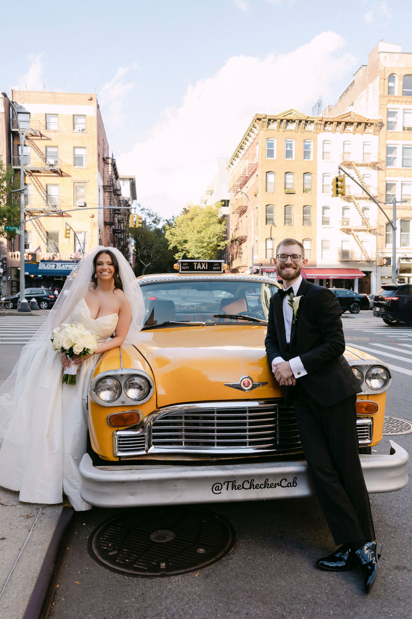 Bride and groom standing by a yellow vintage taxi during wedding portraits in SoHo, New York City