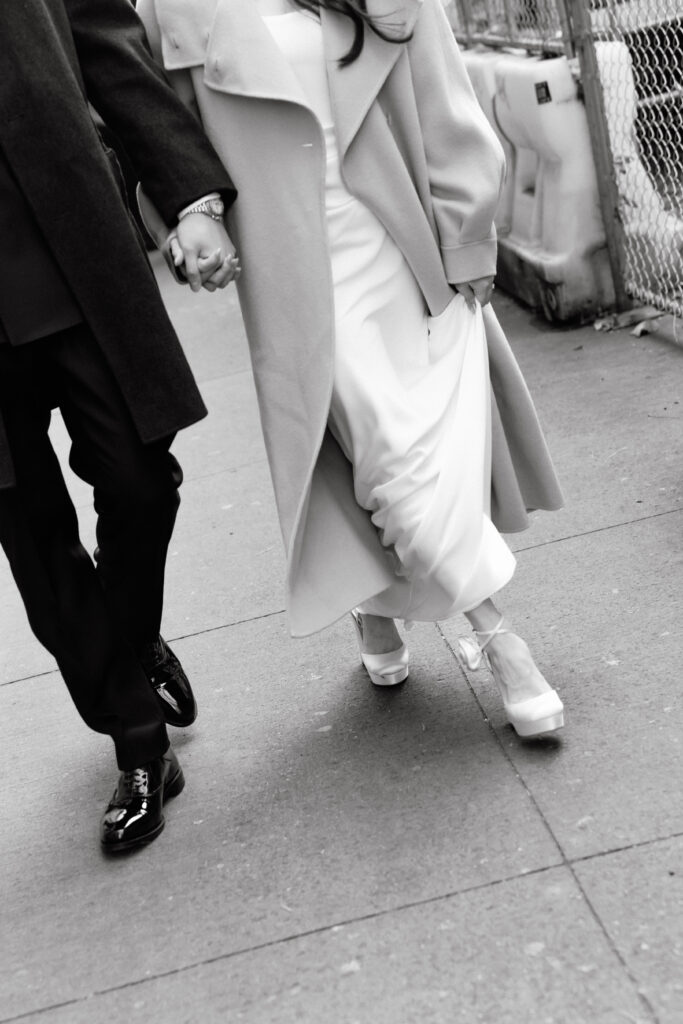 Bride and groom walking hand in hand on a city sidewalk