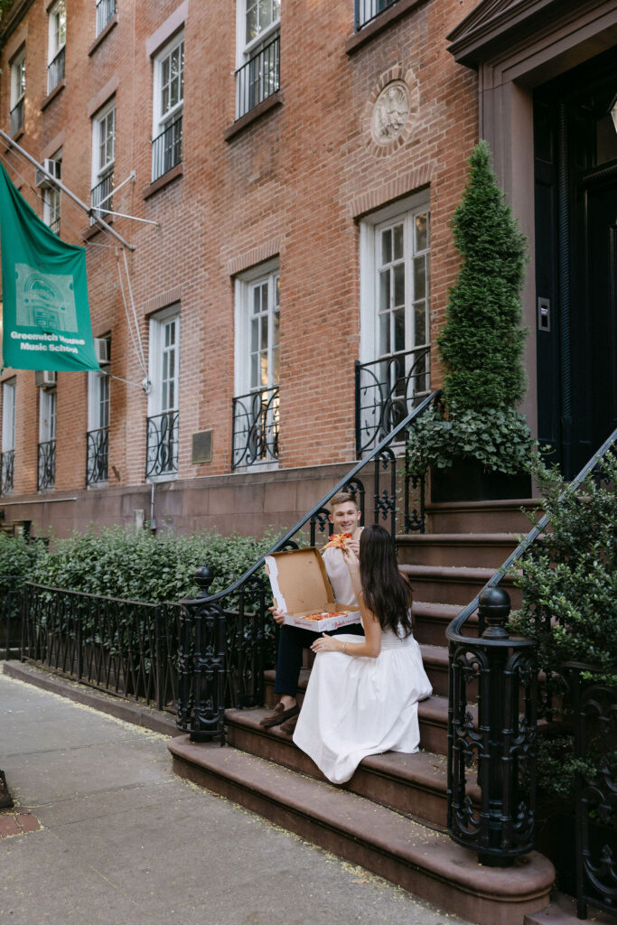 engagement photos of a couple sitting on the steps of a brick townhouse in the west village