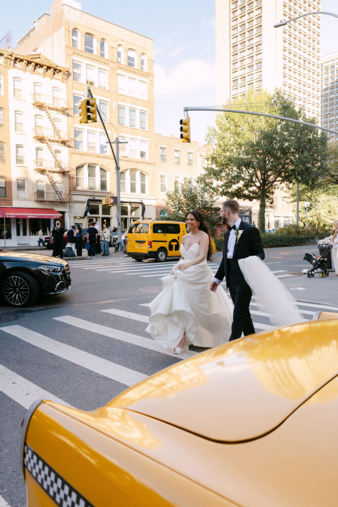Bride and groom crossing a SoHo street next to a yellow taxi on their New York City wedding day