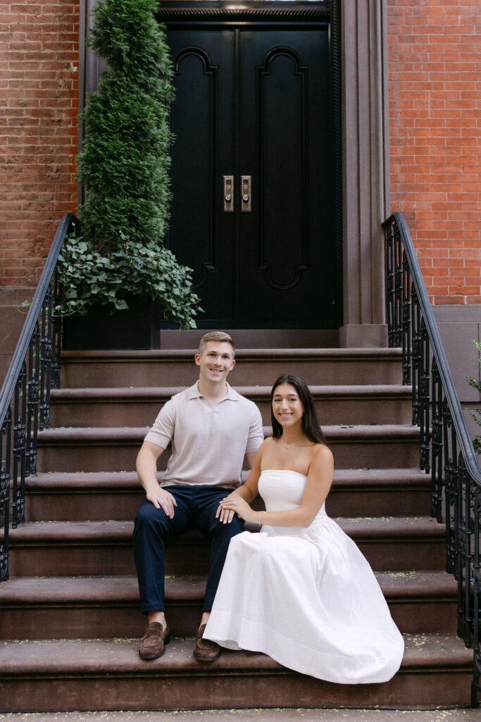 engagement photos of a couple sitting together on townhouse steps in the west village