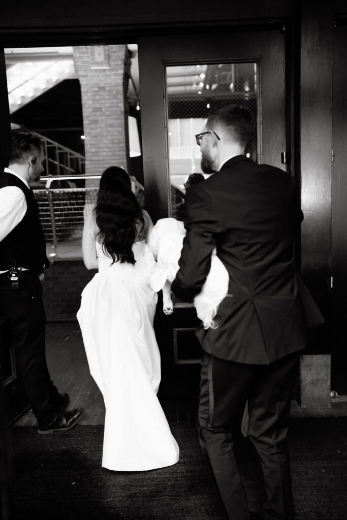 Bride and groom walking hand in hand through the entrance of the SoHo Grand Hotel in New York City
