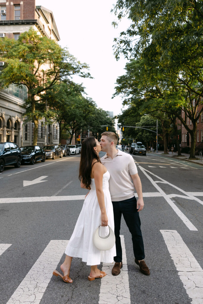 engagement photos of a couple standing together in the middle of a quiet west village street
