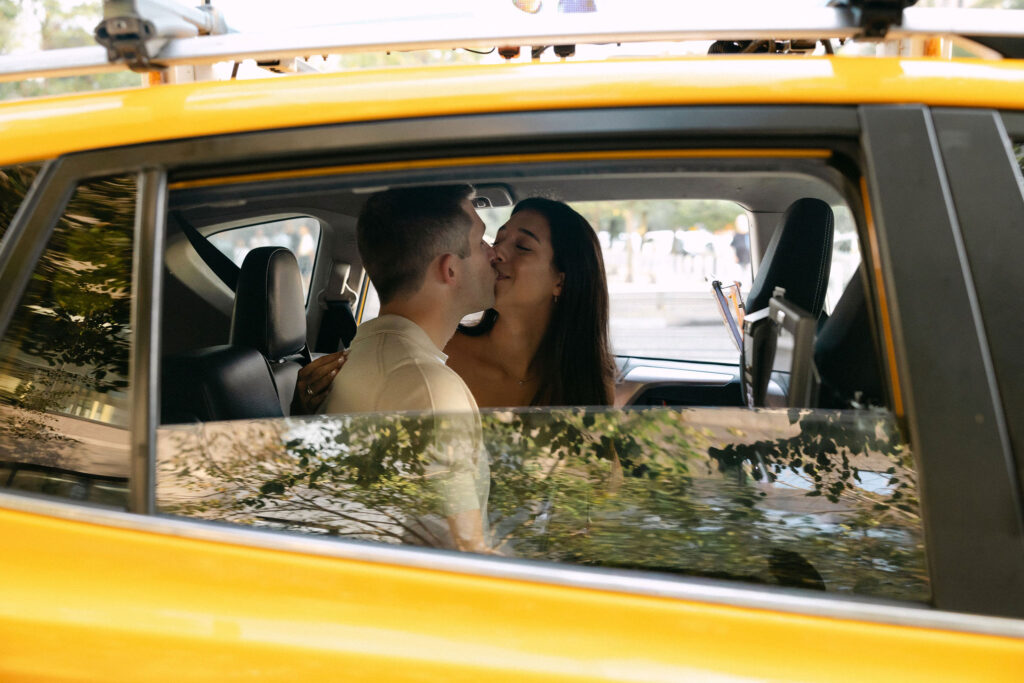 engagement photos of a couple sitting together inside a yellow taxi during a new york city engagement session