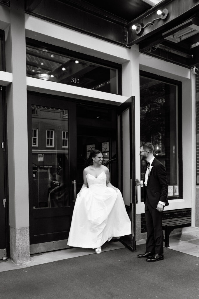 Bride and groom stepping outside their SoHo hotel after their wedding, captured in black and white on a quiet New York City street