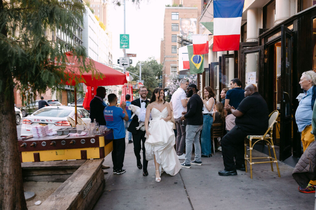 Bride and groom walking through the streets of SoHo with guests after their wedding, surrounded by classic New York City storefronts