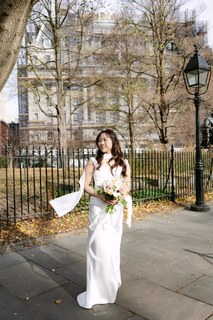 Bride standing alone outdoors holding her wedding bouquet