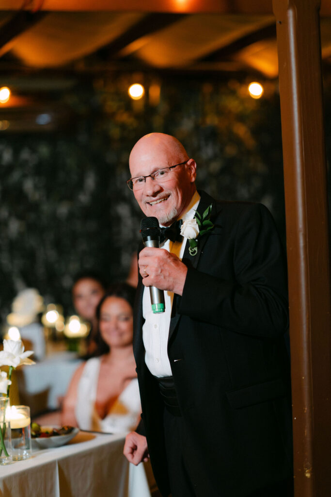 Father giving a heartfelt speech during an intimate candlelit wedding reception in SoHo, New York City.
