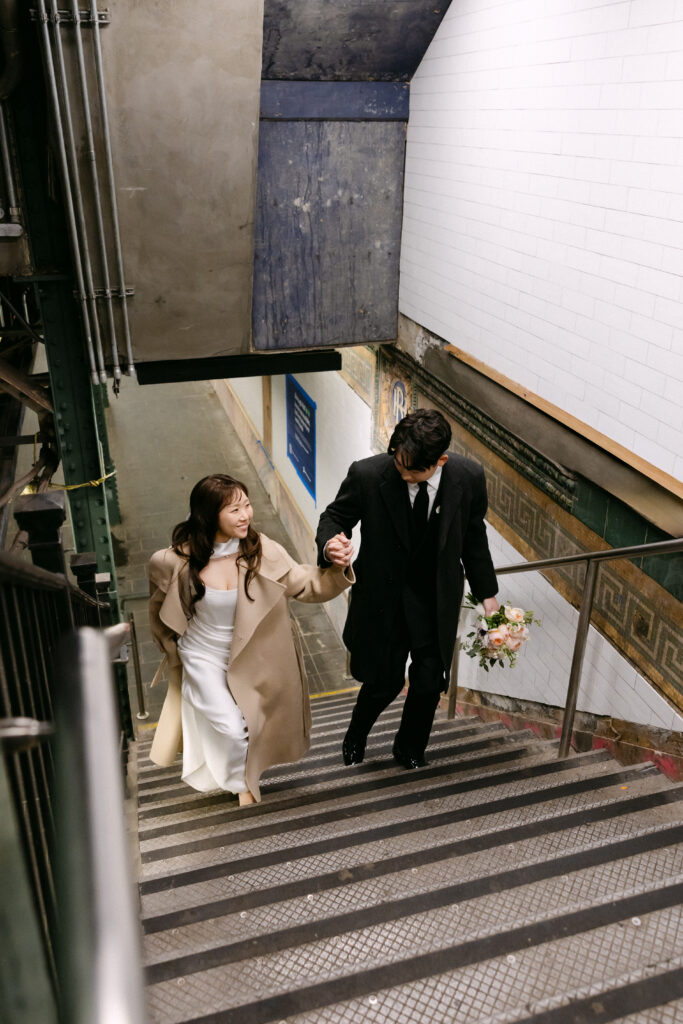 Bride and groom walking down subway stairs in New York City after their wedding