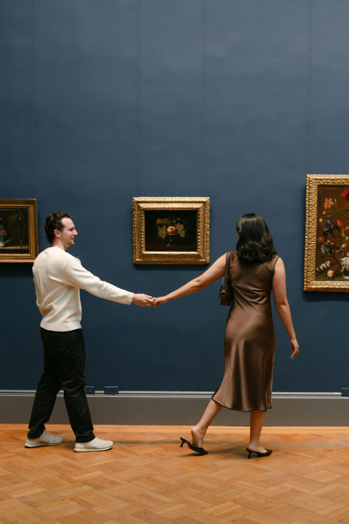nyc engagement session photo of a couple walking hand in hand through an art gallery at the metropolitan museum of art