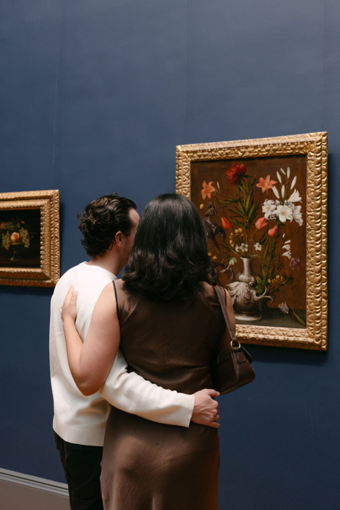 couple standing close together while looking at artwork inside the metropolitan museum of art during an nyc engagement session
