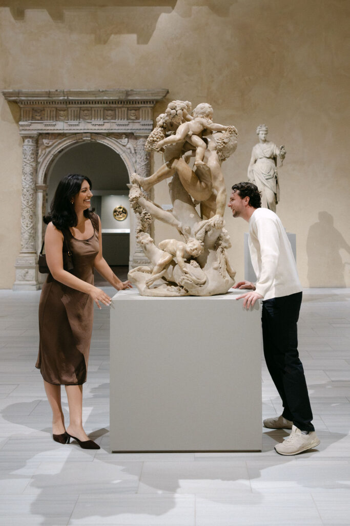 couple standing near a sculpture inside the metropolitan museum of art during an nyc engagement session