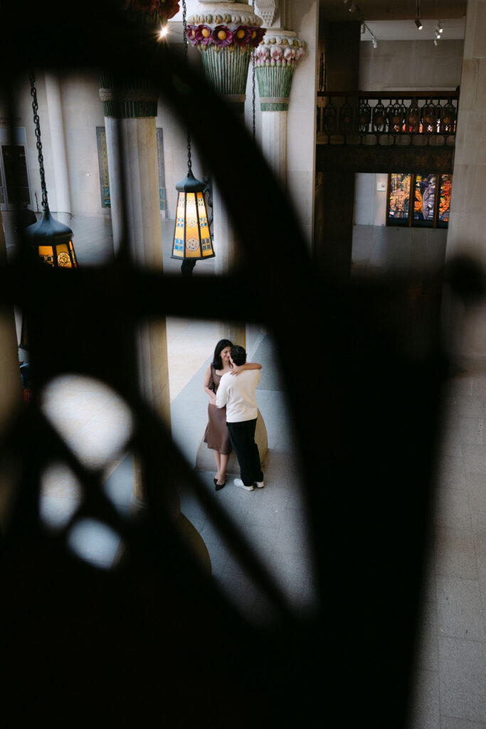 engagement photos of a couple seen through shelves inside a bookstore during an nyc engagement session