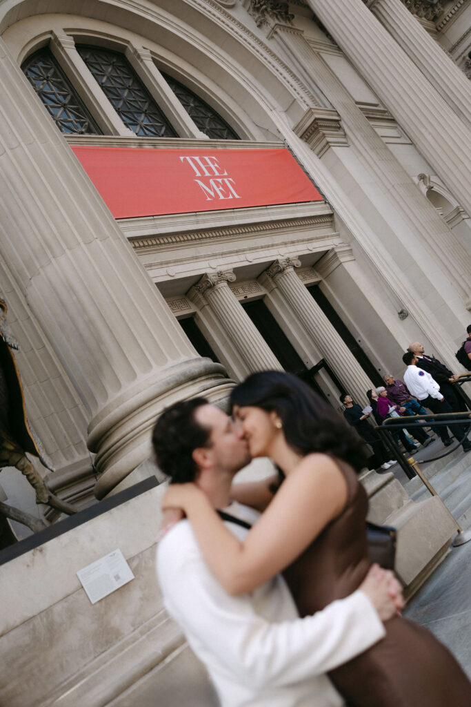 nyc engagement session photo of a couple sharing a kiss outside the metropolitan museum of art

