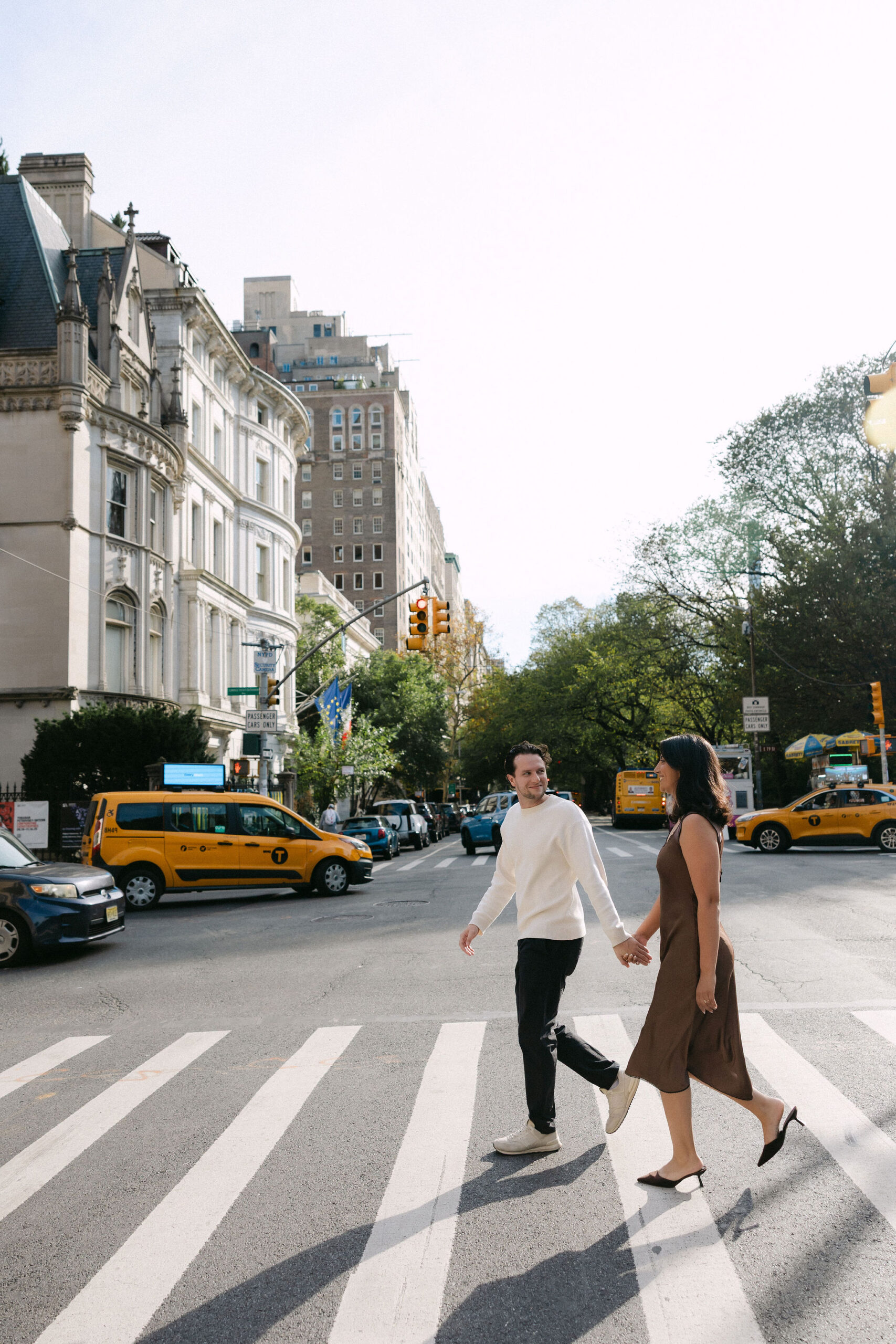 nyc engagement session photos of a couple walking across a city crosswalk in new york
