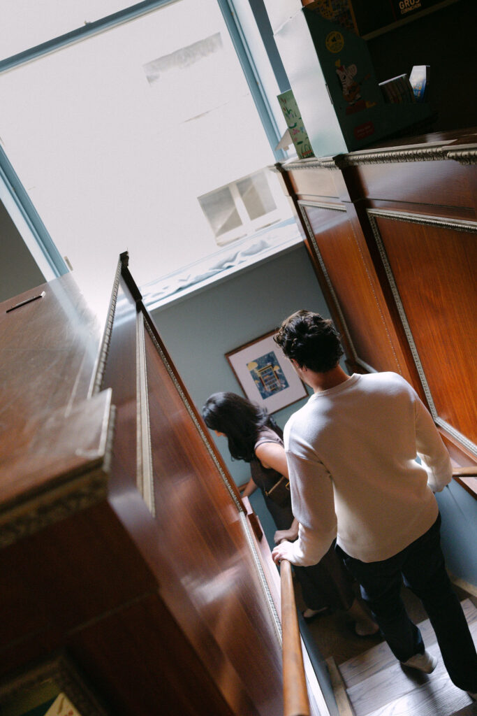 nyc engagement session photo of a couple walking up stairs inside a bookstore