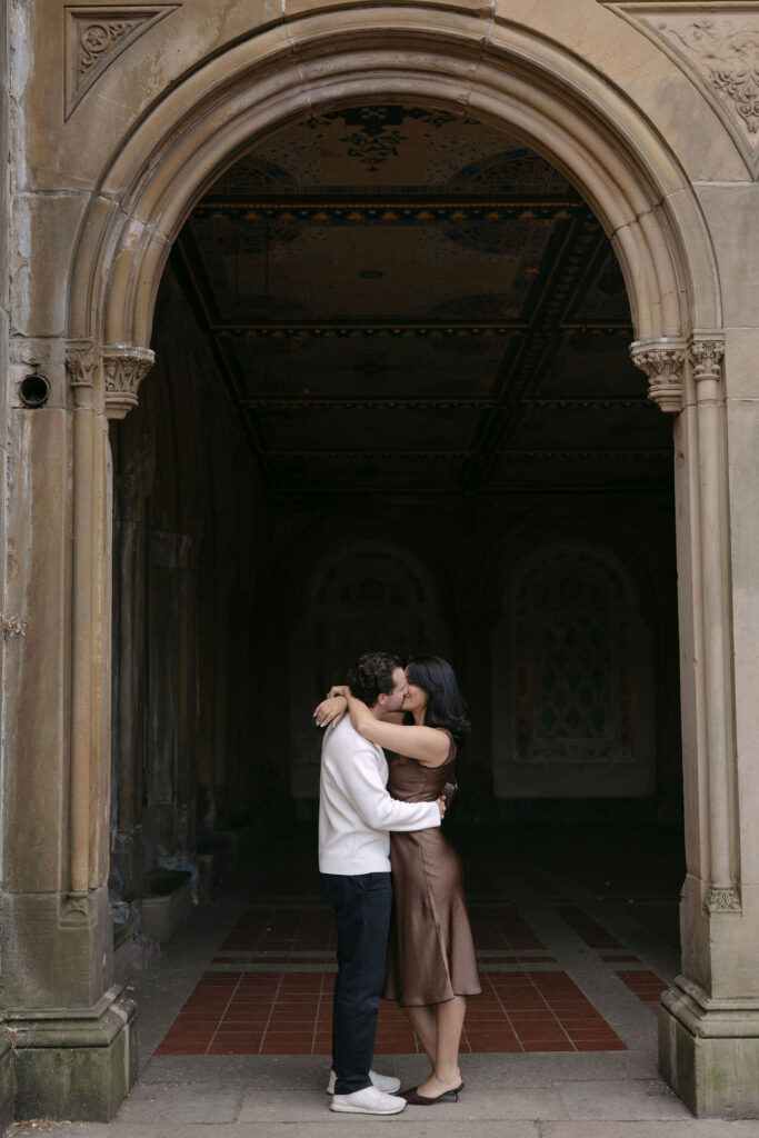nyc engagement session photo of a couple sharing a quiet moment beneath an archway in central park