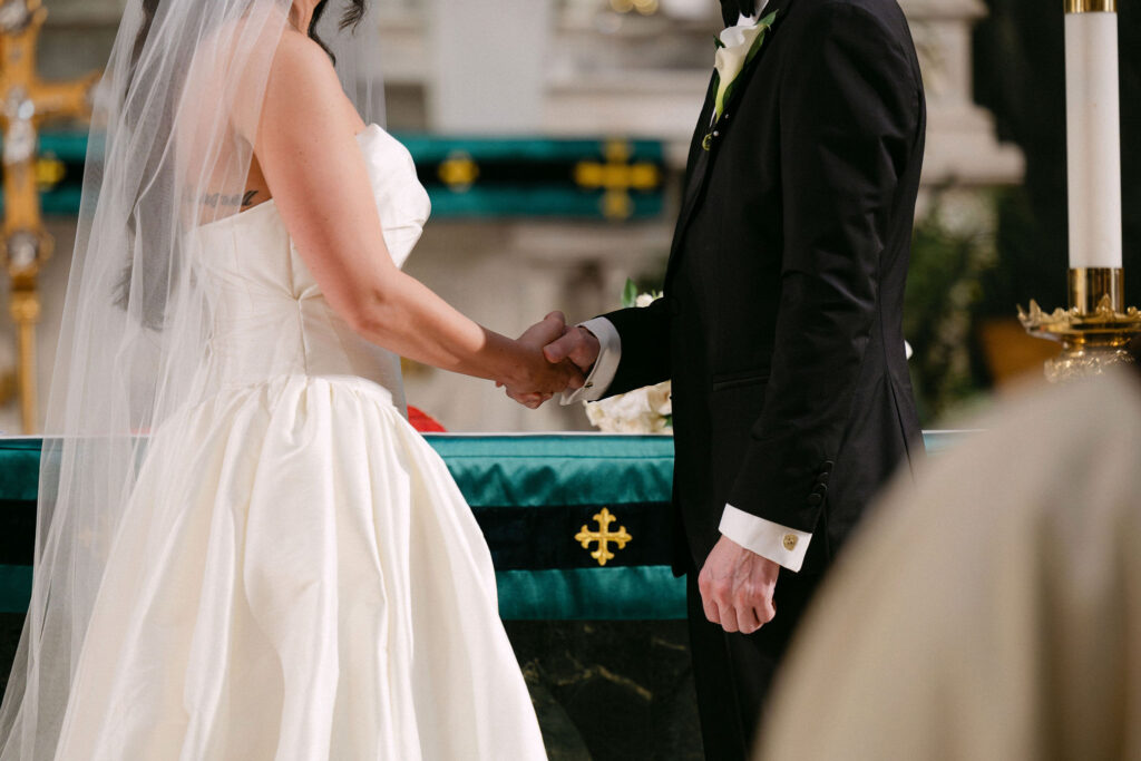 Bride and groom holding hands during their wedding ceremony in a SoHo church in New York City