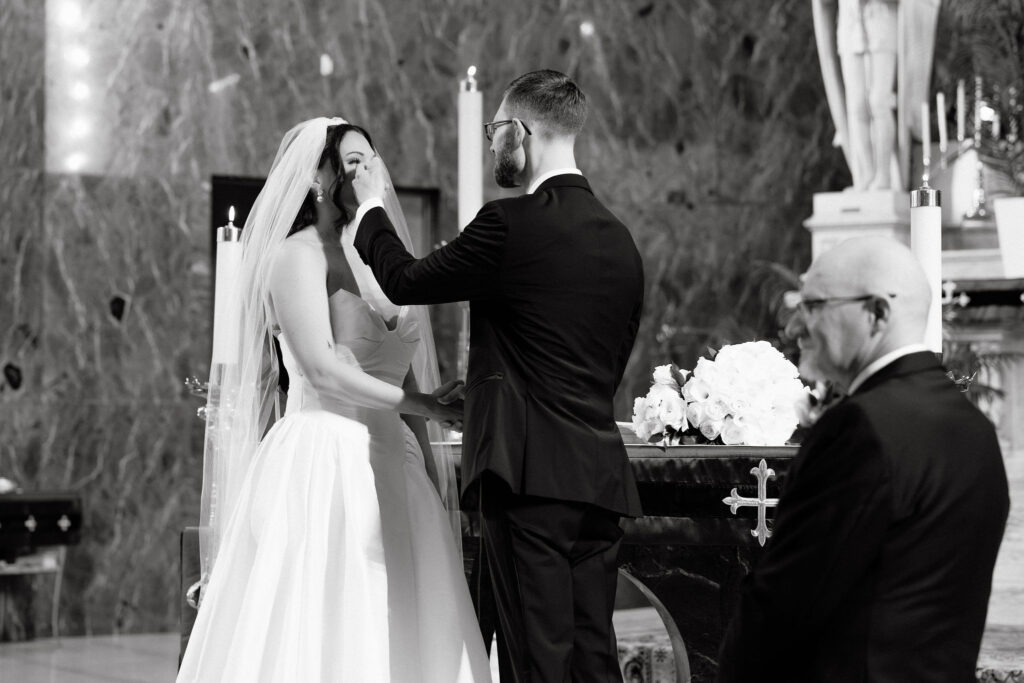 Officiant placing the wedding ring on the bride’s finger during a church ceremony in SoHo, New York City