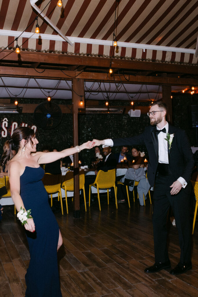 Mother dancing with the groom during an intimate wedding reception in SoHo, New York City, surrounded by warm light and guests.