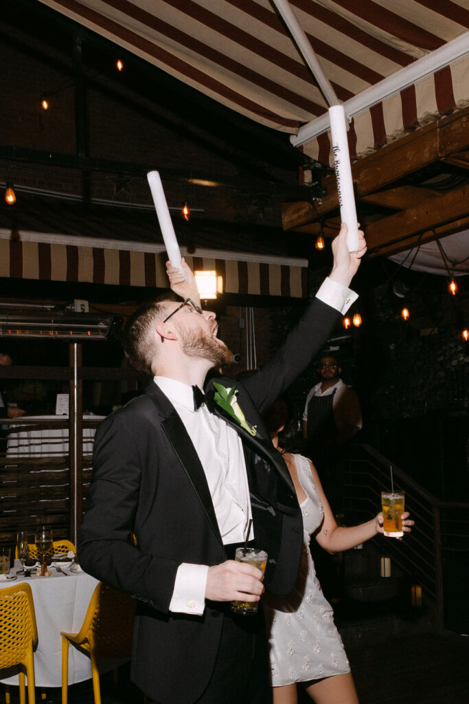 Wedding guests celebrating with glow sticks during a lively late-night wedding reception in SoHo, New York City.
