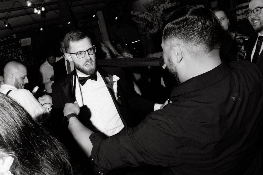 Groom sharing a candid moment with guests during a late-night wedding reception in SoHo, New York City, captured in black and white.