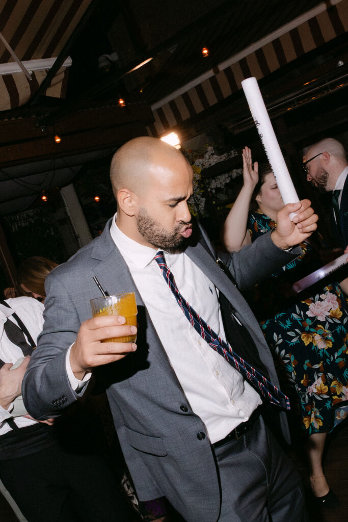 Wedding guest dancing with a drink during a lively late-night wedding reception in SoHo, New York City.