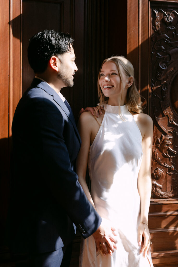 Couple smiling together inside New York Public Library during romantic NYC engagement photos