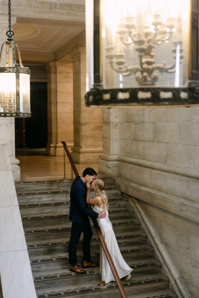 Couple on marble staircase inside New York Public Library during romantic NYC engagement session
