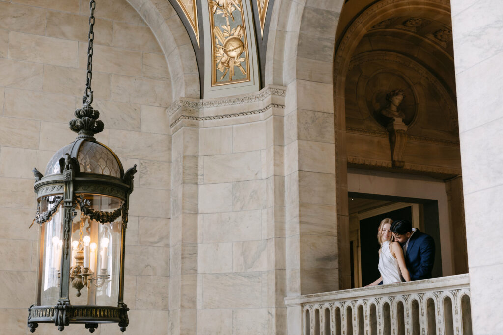 Couple standing on balcony inside New York Public Library during NYC engagement photos