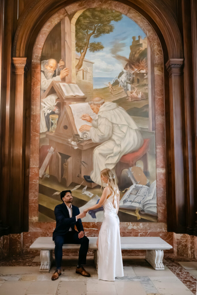 Couple standing in front of mural inside New York Public Library during NYC engagement session