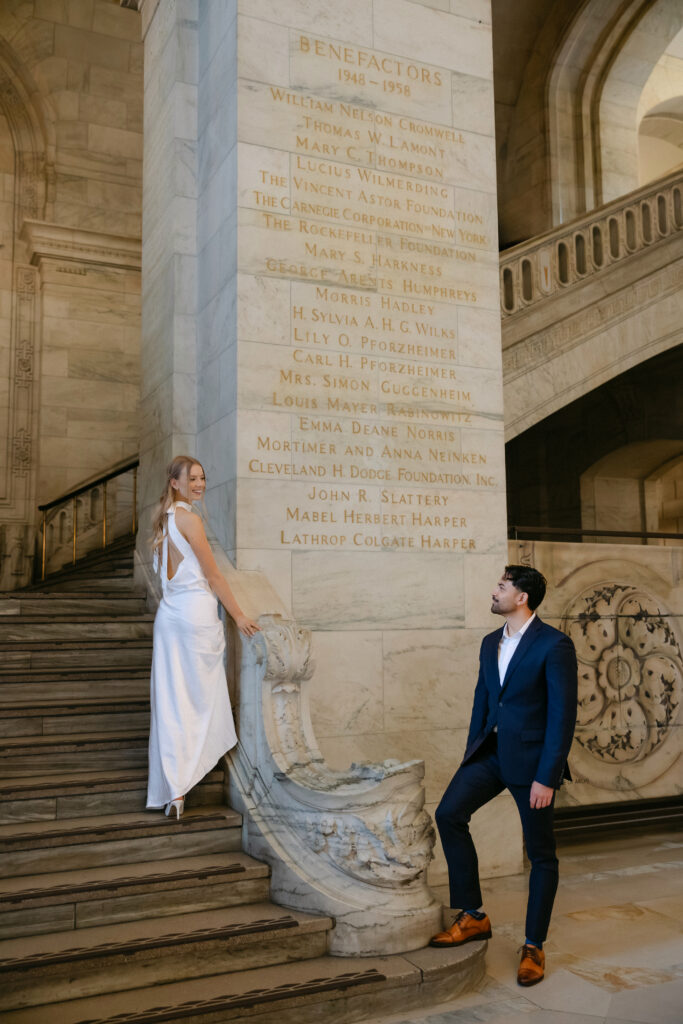 Couple on marble staircase inside New York Public Library during romantic NYC engagement photos

