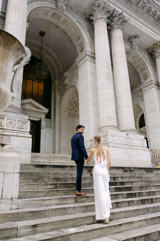 Couple facing each other on steps of New York Public Library during NYC engagement photos
